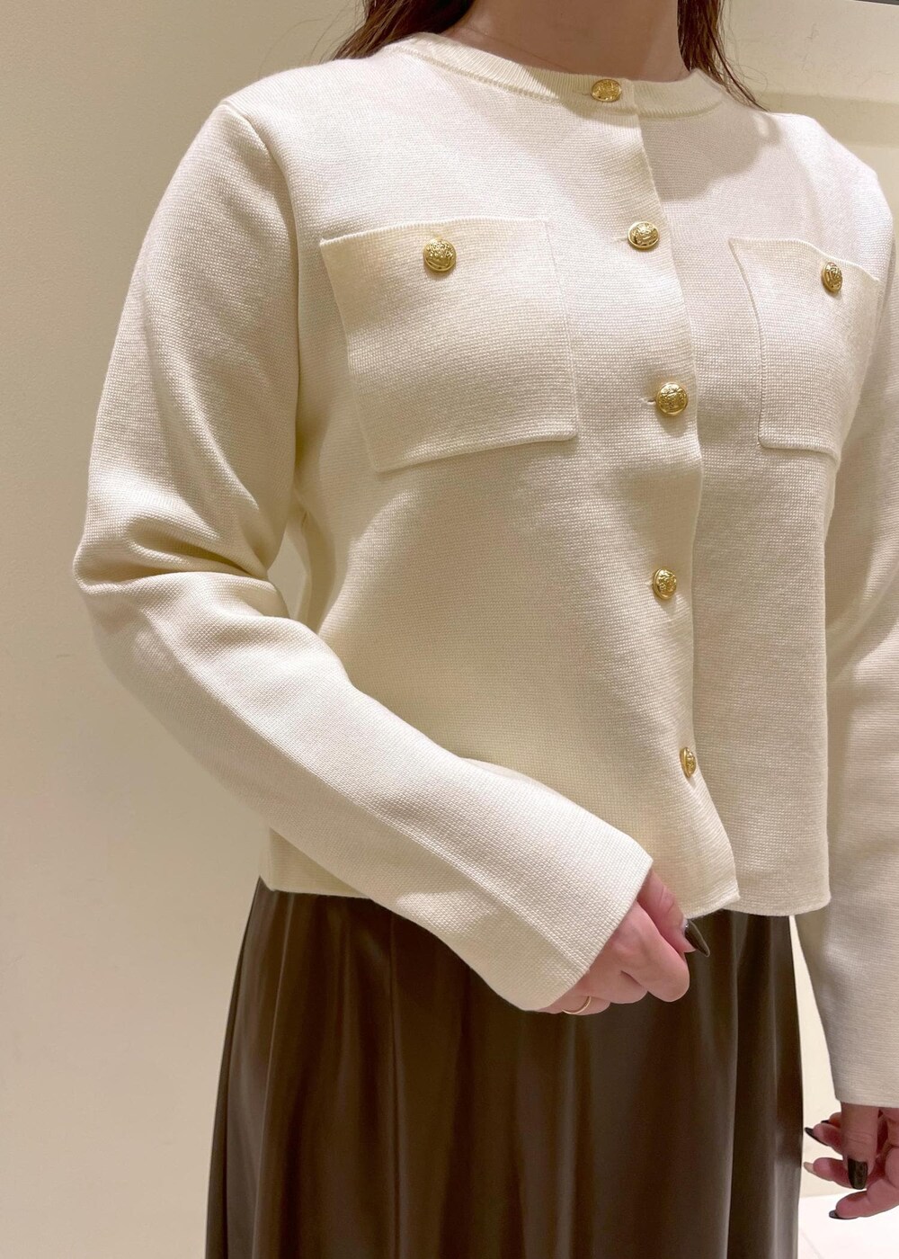 ブラック系のショルダーバッグ、ブラウン系のスカート、ホワイト系のカーディガン/ボレロを着用したレディースの秋コーディネートの5枚目の写真