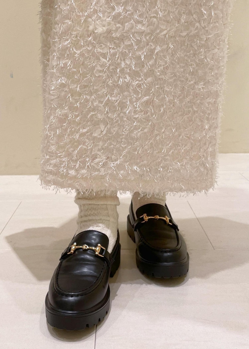 ブラック系のショルダーバッグ、ホワイト系のスカート、ブラック系のローファーを着用したレディースの秋コーディネートの10枚目の写真