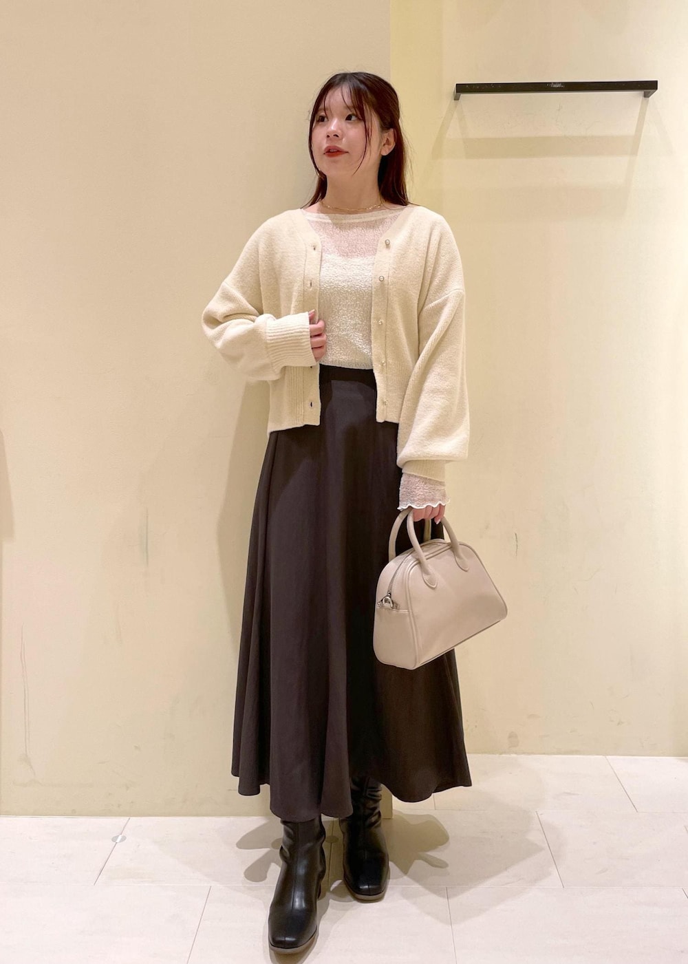 グレー系のスカート、ホワイト系のカーディガン/ボレロ、ホワイト系のTシャツ/カットソーを着用したレディースの秋コーディネートの10枚目の写真