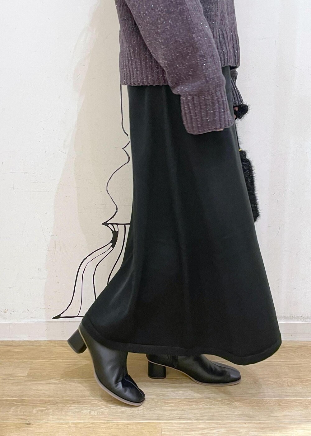 ブラック系のワンピース、グレー系のニット/セーター、ブラック系のブーツを着用したレディースの冬コーディネートの6枚目の写真