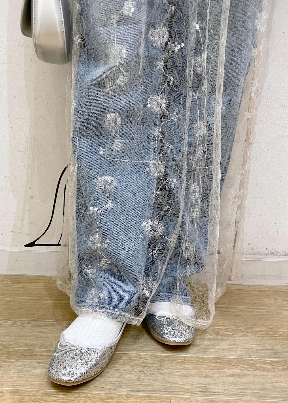 ブルー系のデニムパンツ、ホワイト系のスカート、シルバー系のハンドバッグを着用したレディースの冬コーディネートの8枚目の写真