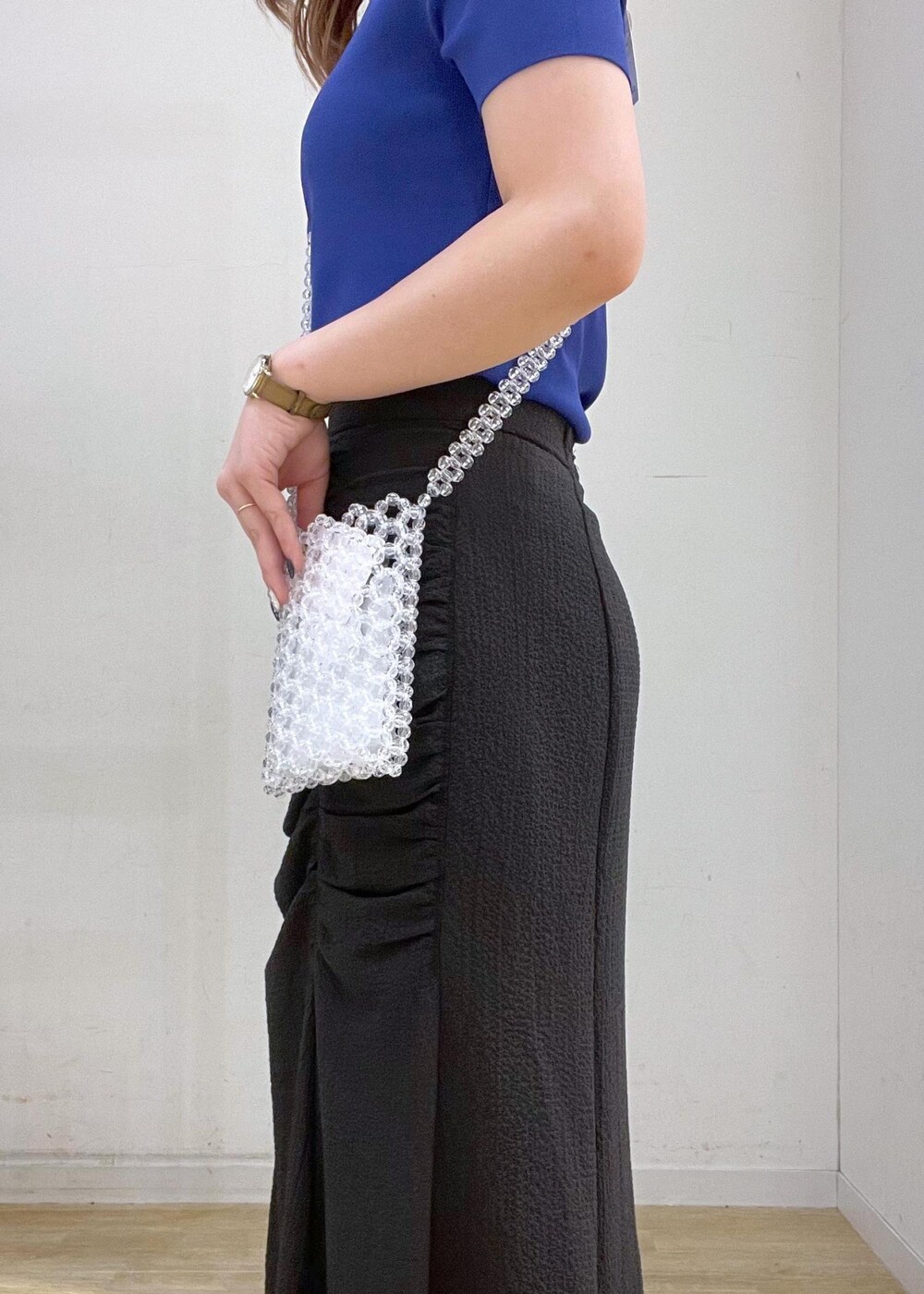 グレー系のスカート、ブルー系のニット/セーター、ゴールド系のサンダルを着用したレディースの夏コーディネートの3枚目の写真