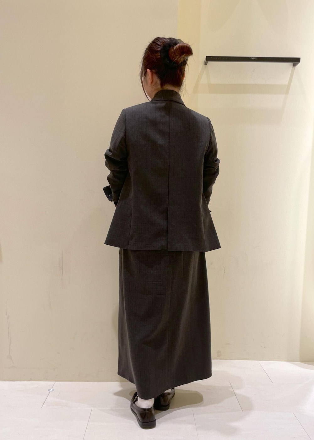 ブラック系のスカート、ブラック系のテーラードジャケット、ベージュ系のTシャツ/カットソーを着用したレディースの秋コーディネートの4枚目の写真