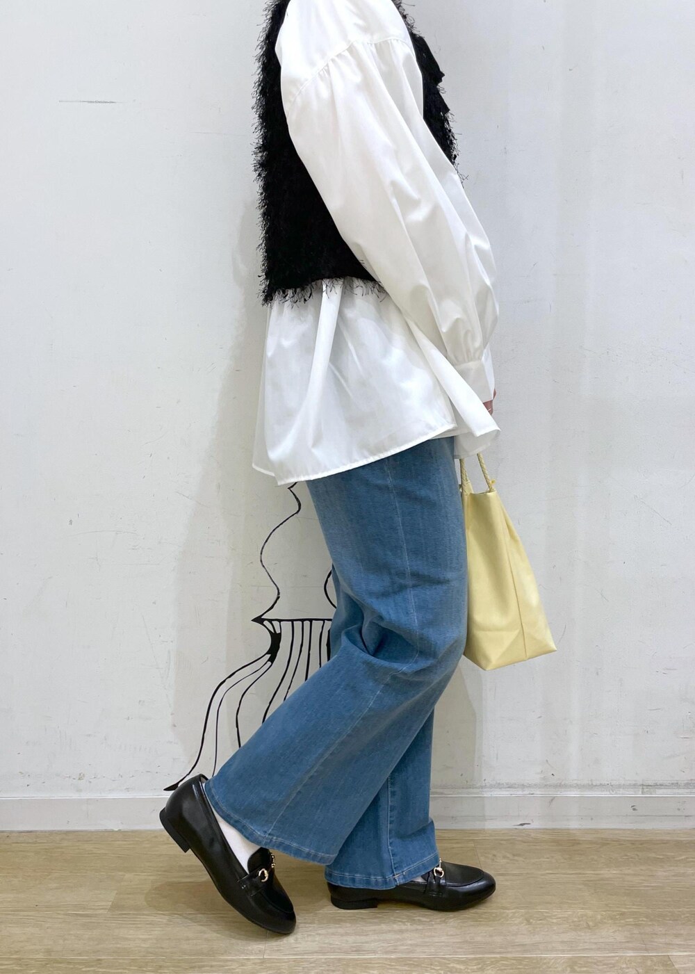 ブラック系のベスト、ブルー系のデニムパンツ、イエロー系のトートバッグを着用したレディースの冬コーディネートの8枚目の写真