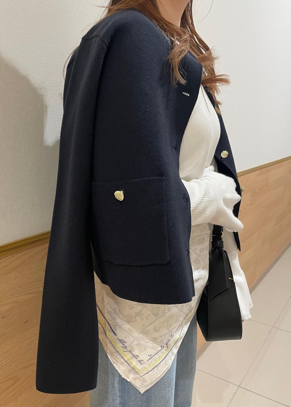 ブルー系のカーディガン/ボレロ、ホワイト系のニット/セーター、ブラック系のハンドバッグを着用したレディースの春コーディネートの6枚目の写真