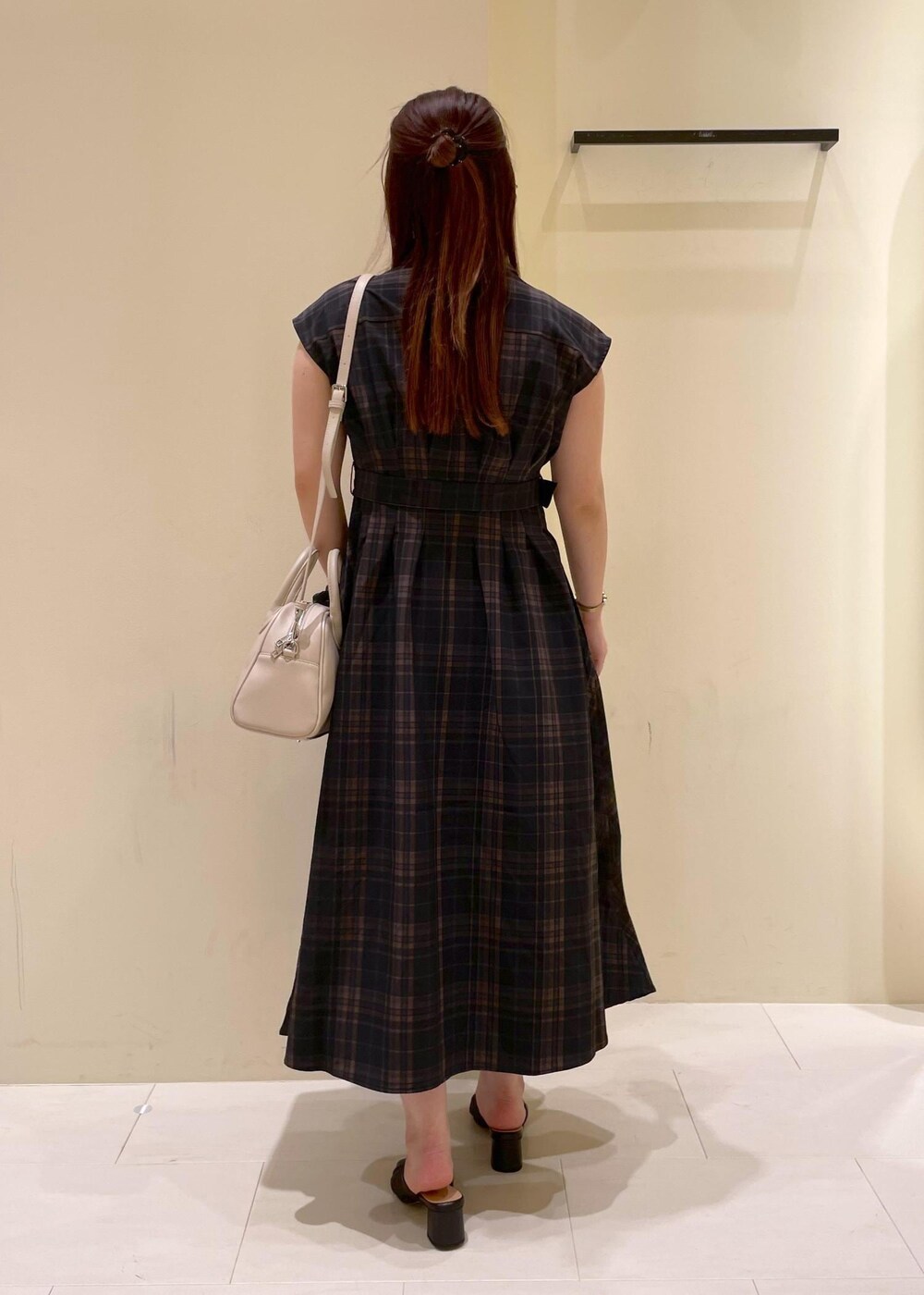 ブラック系のパンプス、ブラック系のワンピース、ベージュ系のボストンバッグを着用したレディースの夏コーディネートの2枚目の写真