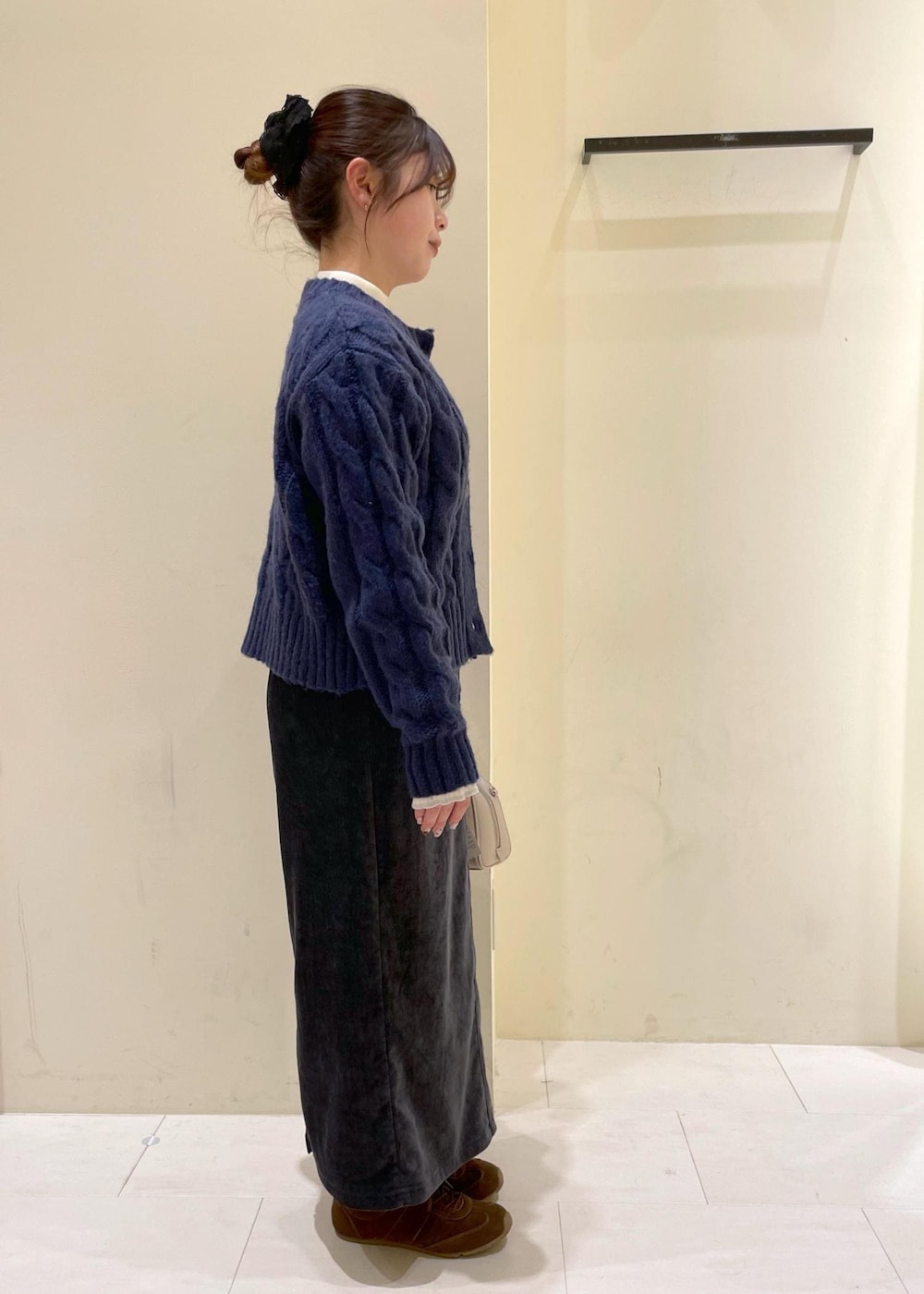 グレー系のスカート、ブルー系のカーディガン/ボレロ、ホワイト系のニット/セーターを着用したレディースの冬コーディネートの2枚目の写真