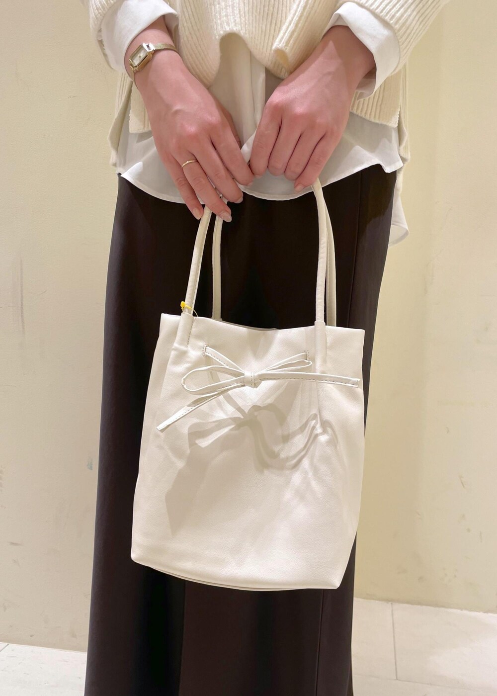 シルバー系のバレエシューズ、ホワイト系のニット/セーター、ホワイト系のトートバッグを着用したレディースの冬コーディネートの6枚目の写真