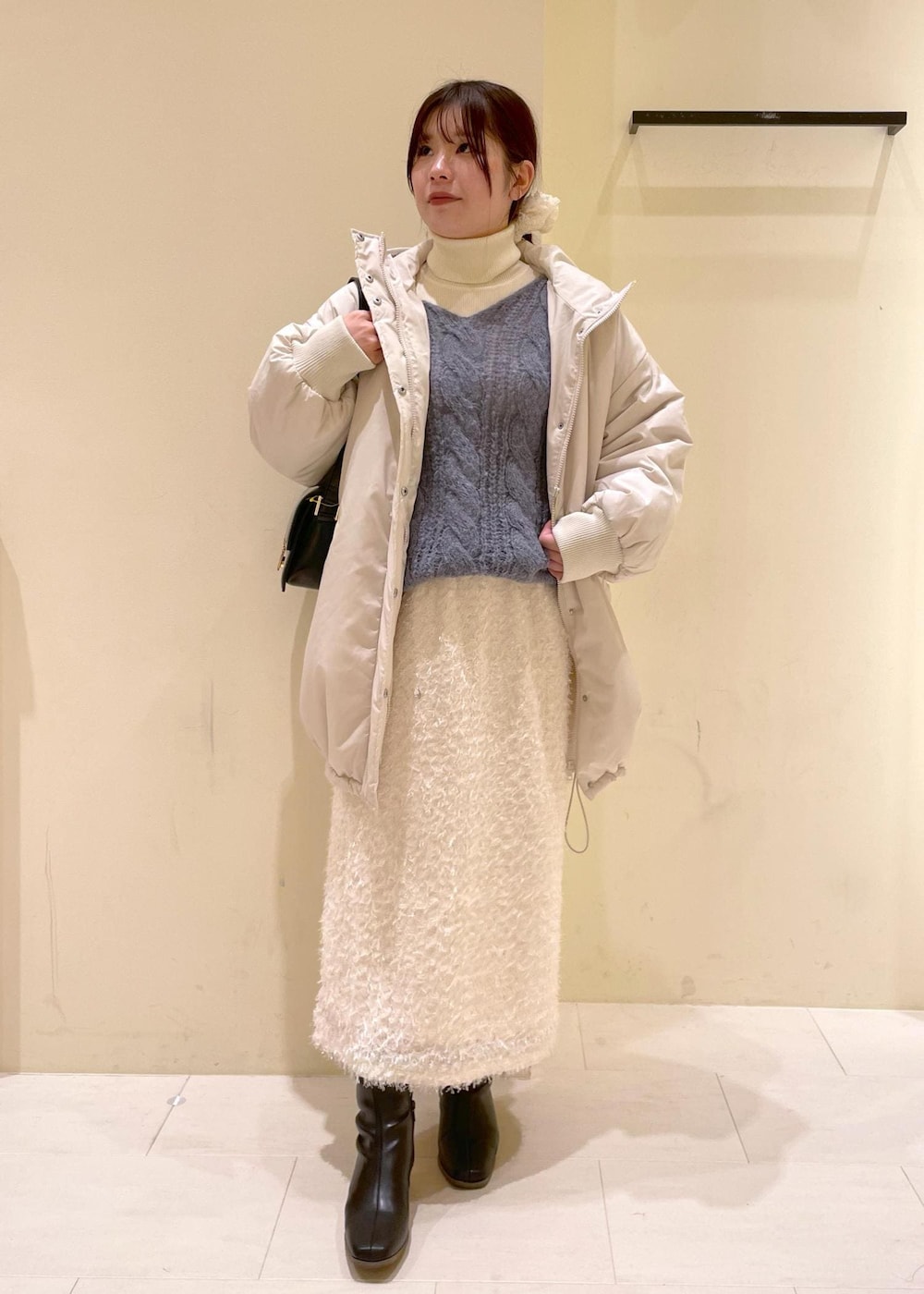 ブラック系のショルダーバッグ、ホワイト系のニット/セーター、ブラック系のブーツを着用したレディースの秋コーディネートの10枚目の写真