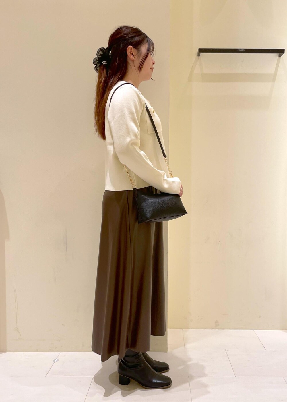 ブラック系のショルダーバッグ、ブラウン系のスカート、ホワイト系のカーディガン/ボレロを着用したレディースの秋コーディネートの3枚目の写真