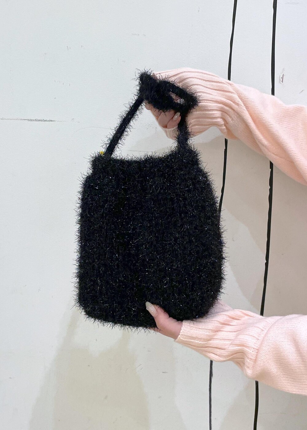 ピンク系のニット/セーター、ブラック系のブーツ、ブラック系のショルダーバッグを着用したレディースの冬コーディネートの7枚目の写真