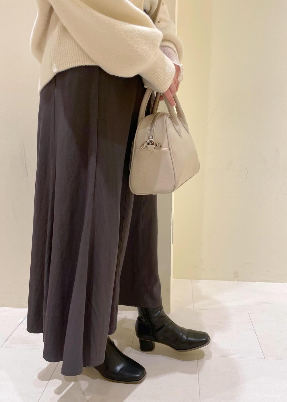 グレー系のスカート、ホワイト系のカーディガン/ボレロ、ホワイト系のTシャツ/カットソーを着用したレディースの秋コーディネートの7枚目の写真