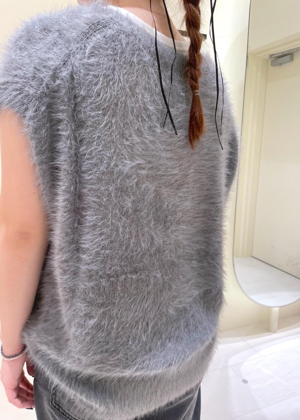 ホワイト系のタンクトップ、グレー系のベスト、ブラック系のブーツを着用したレディースの秋コーディネートの7枚目の写真