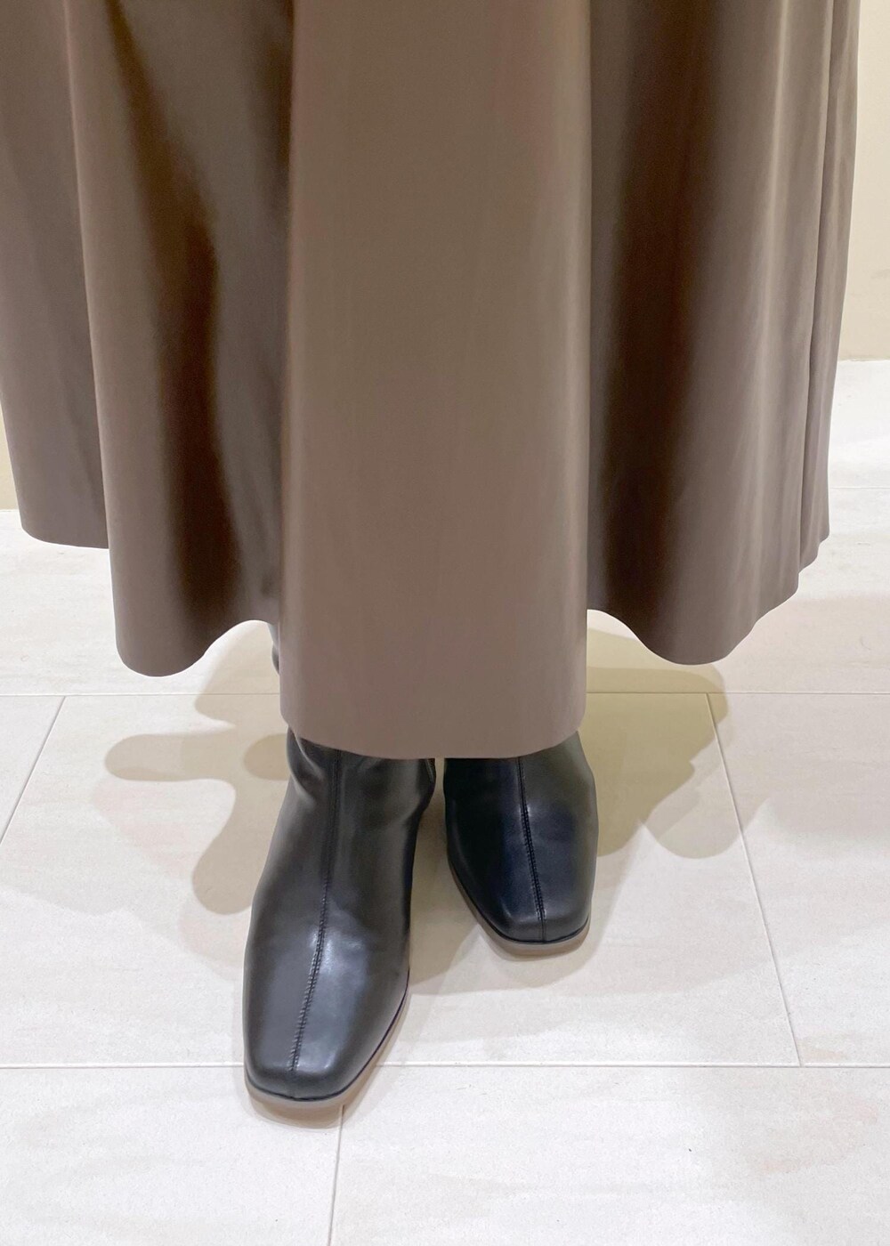 ブラック系のショルダーバッグ、ブラウン系のスカート、ホワイト系のカーディガン/ボレロを着用したレディースの秋コーディネートの8枚目の写真