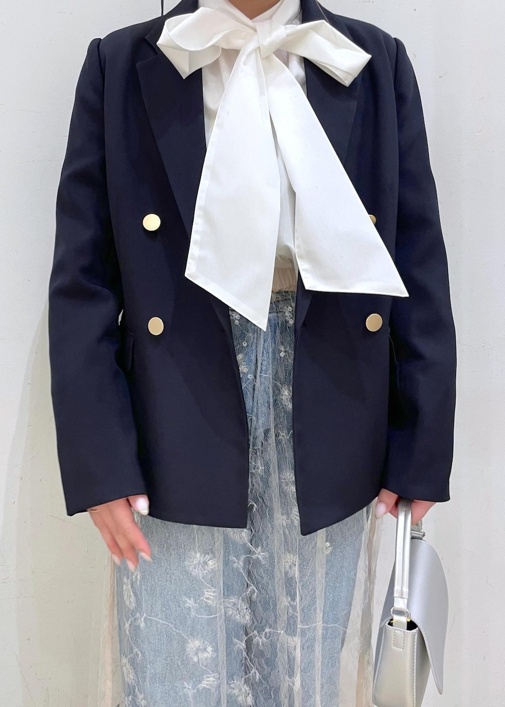 ブルー系のデニムパンツ、ホワイト系のスカート、シルバー系のハンドバッグを着用したレディースの冬コーディネートの4枚目の写真