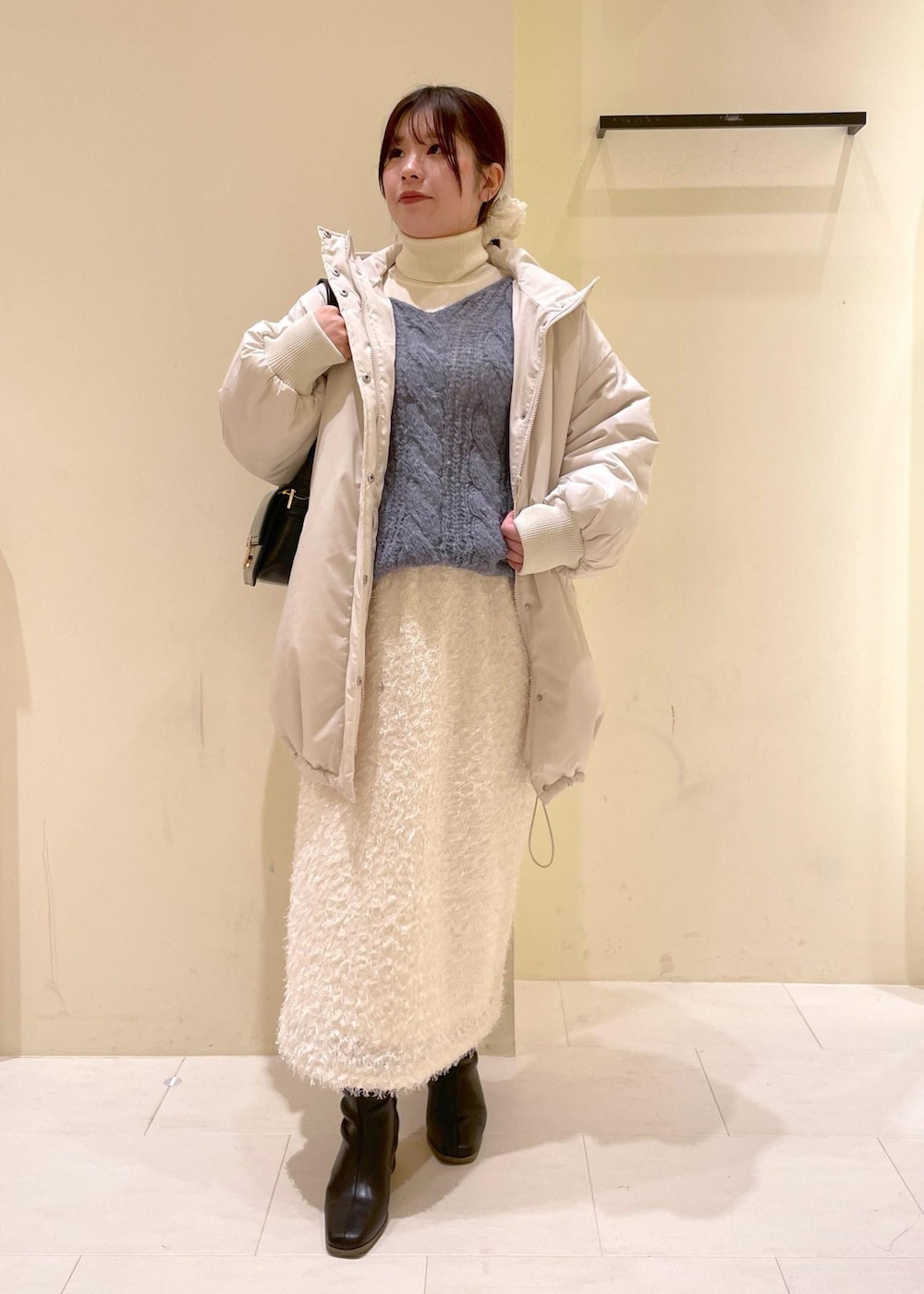 ブラック系のショルダーバッグ、ホワイト系のニット/セーター、ブラック系のブーツを着用したレディースの秋コーディネートの4枚目の写真