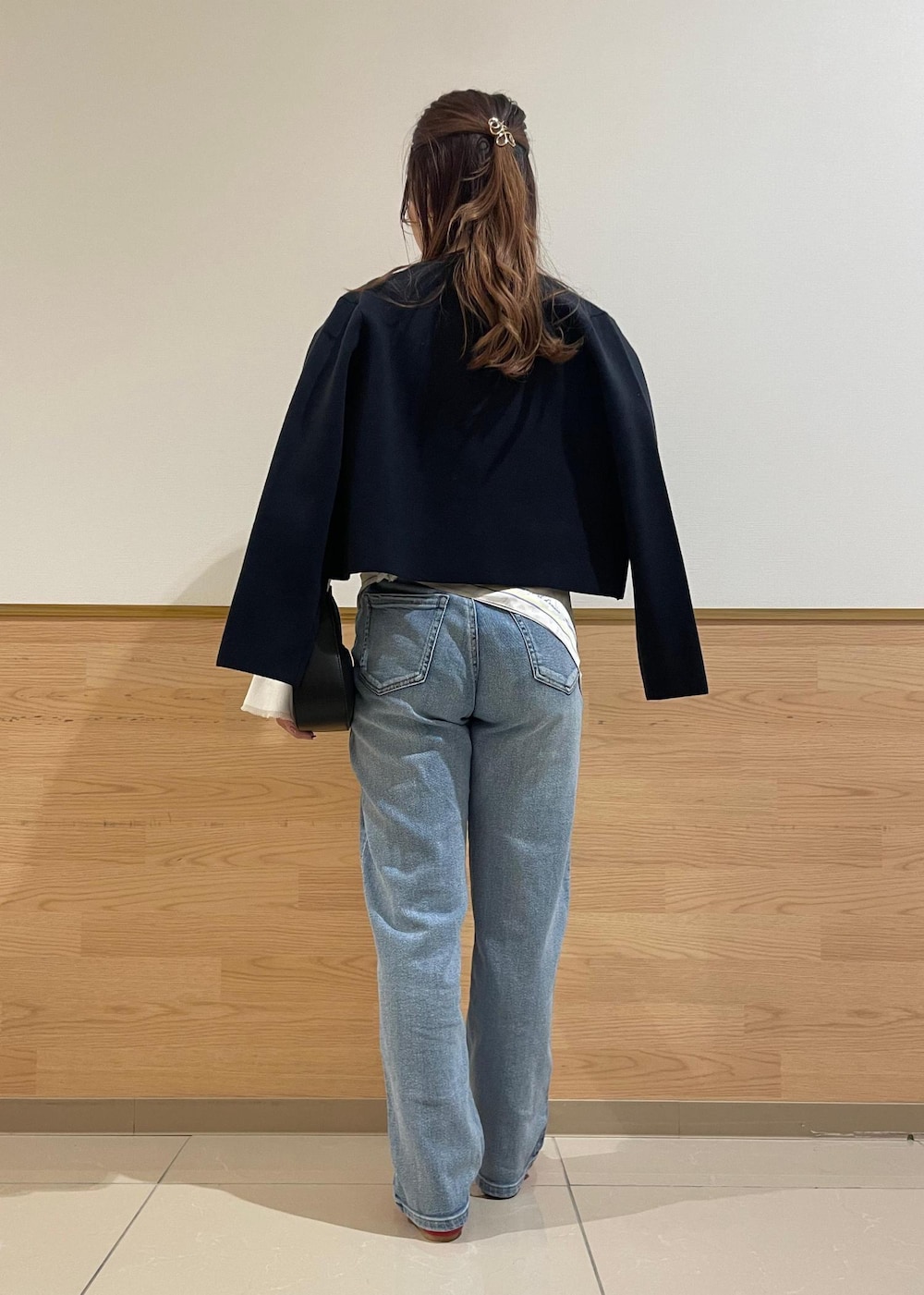 ブルー系のカーディガン/ボレロ、ホワイト系のニット/セーター、ブラック系のハンドバッグを着用したレディースの春コーディネートの2枚目の写真