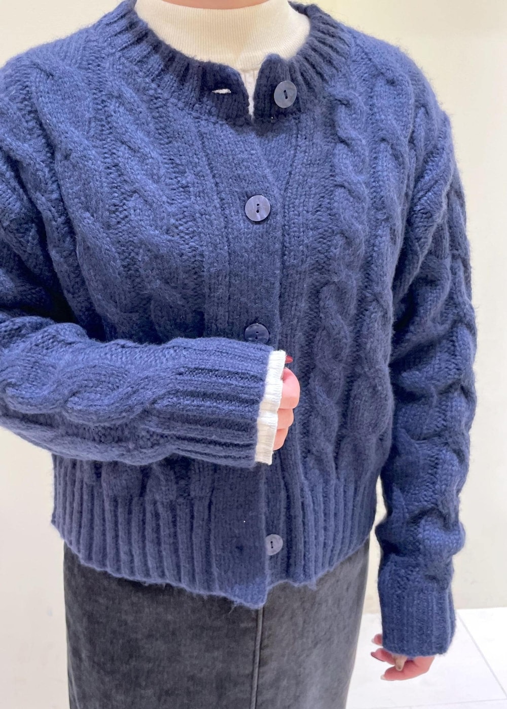 グレー系のスカート、ブルー系のカーディガン/ボレロ、ホワイト系のニット/セーターを着用したレディースの冬コーディネートの5枚目の写真