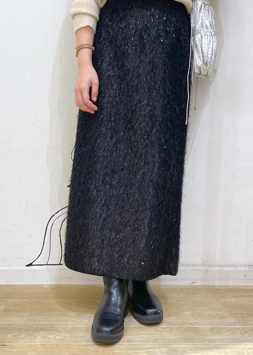 ブラック系のスカート、ベージュ系のニット/セーター、ブラック系のブーツを着用したレディースの冬コーディネートの7枚目の写真