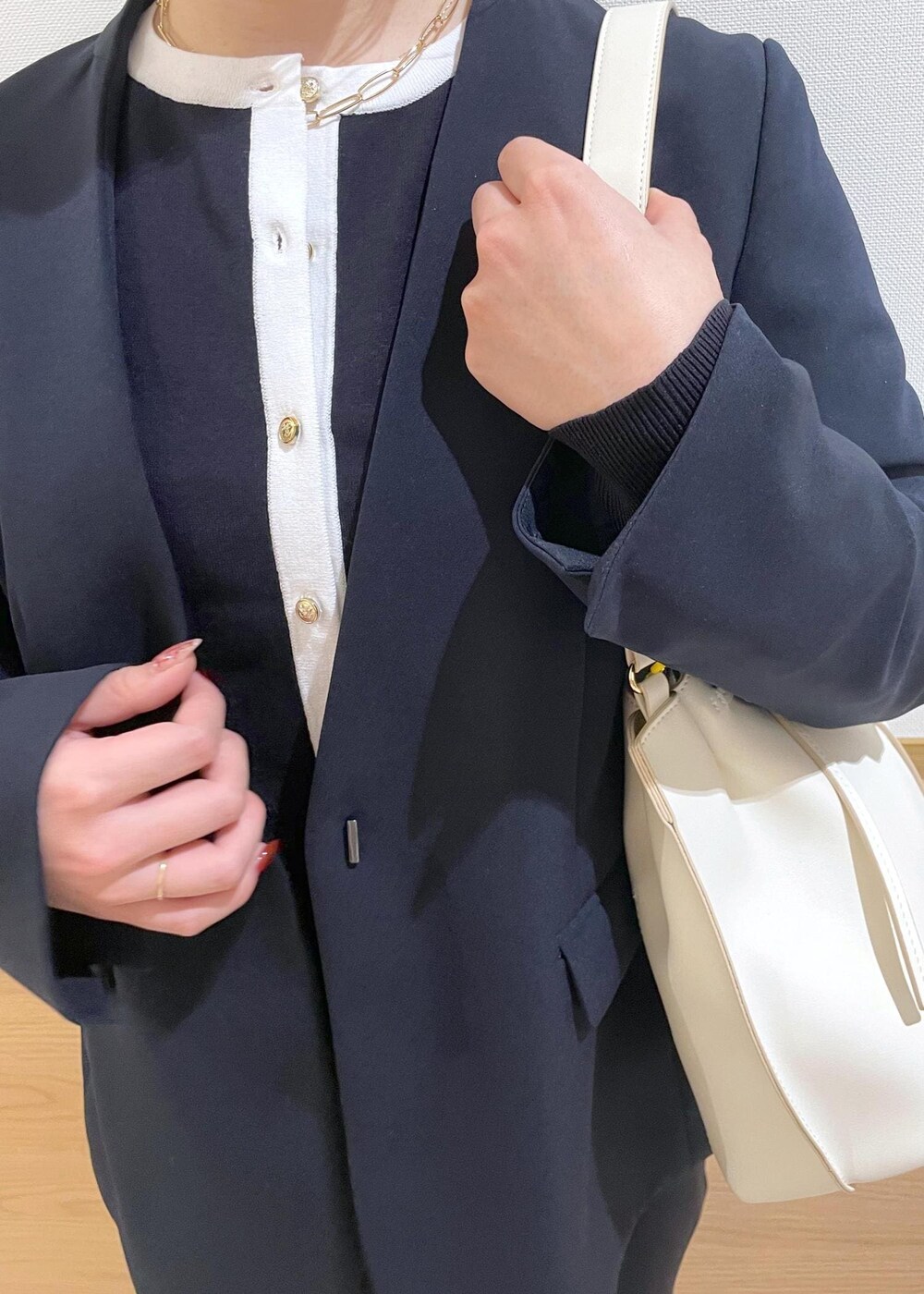 ホワイト系のハンドバッグ、ブラック系のパンプス、ブルー系のノーカラージャケットを着用したレディースの春コーディネートの5枚目の写真