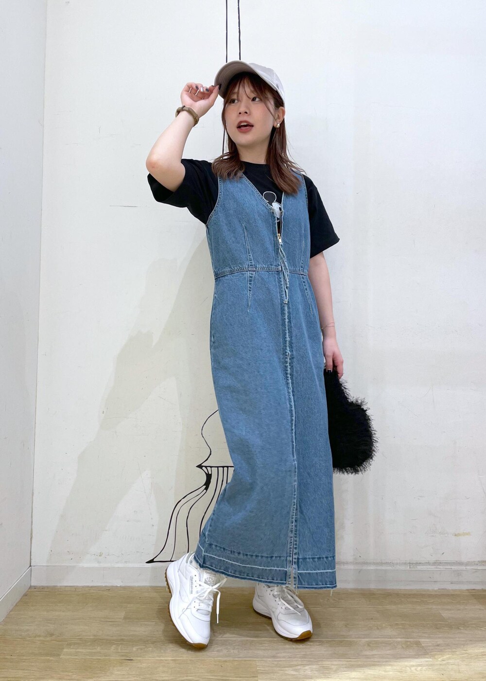 ホワイト系のスニーカー、ブラック系のハンドバッグ、ブルー系のジャンパースカートを着用したレディースの夏コーディネートの4枚目の写真