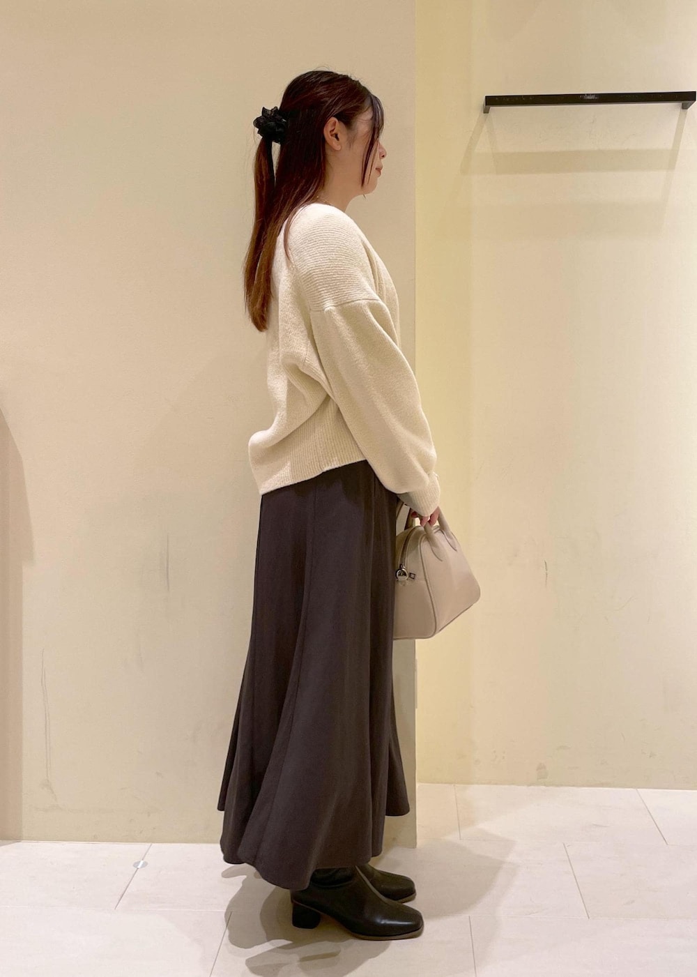 グレー系のスカート、ホワイト系のカーディガン/ボレロ、ホワイト系のTシャツ/カットソーを着用したレディースの秋コーディネートの3枚目の写真
