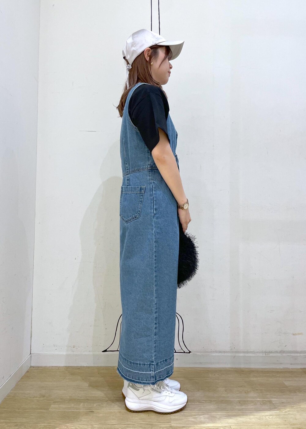 ホワイト系のスニーカー、ブラック系のハンドバッグ、ブルー系のジャンパースカートを着用したレディースの夏コーディネートの3枚目の写真