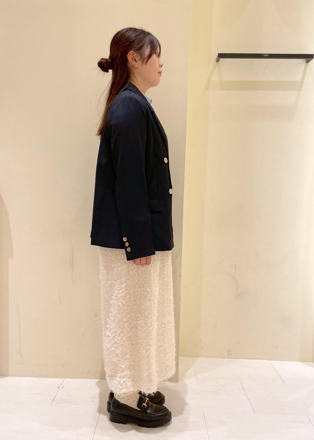 ブラック系のショルダーバッグ、ホワイト系のスカート、ブラック系のローファーを着用したレディースの秋コーディネートの4枚目の写真