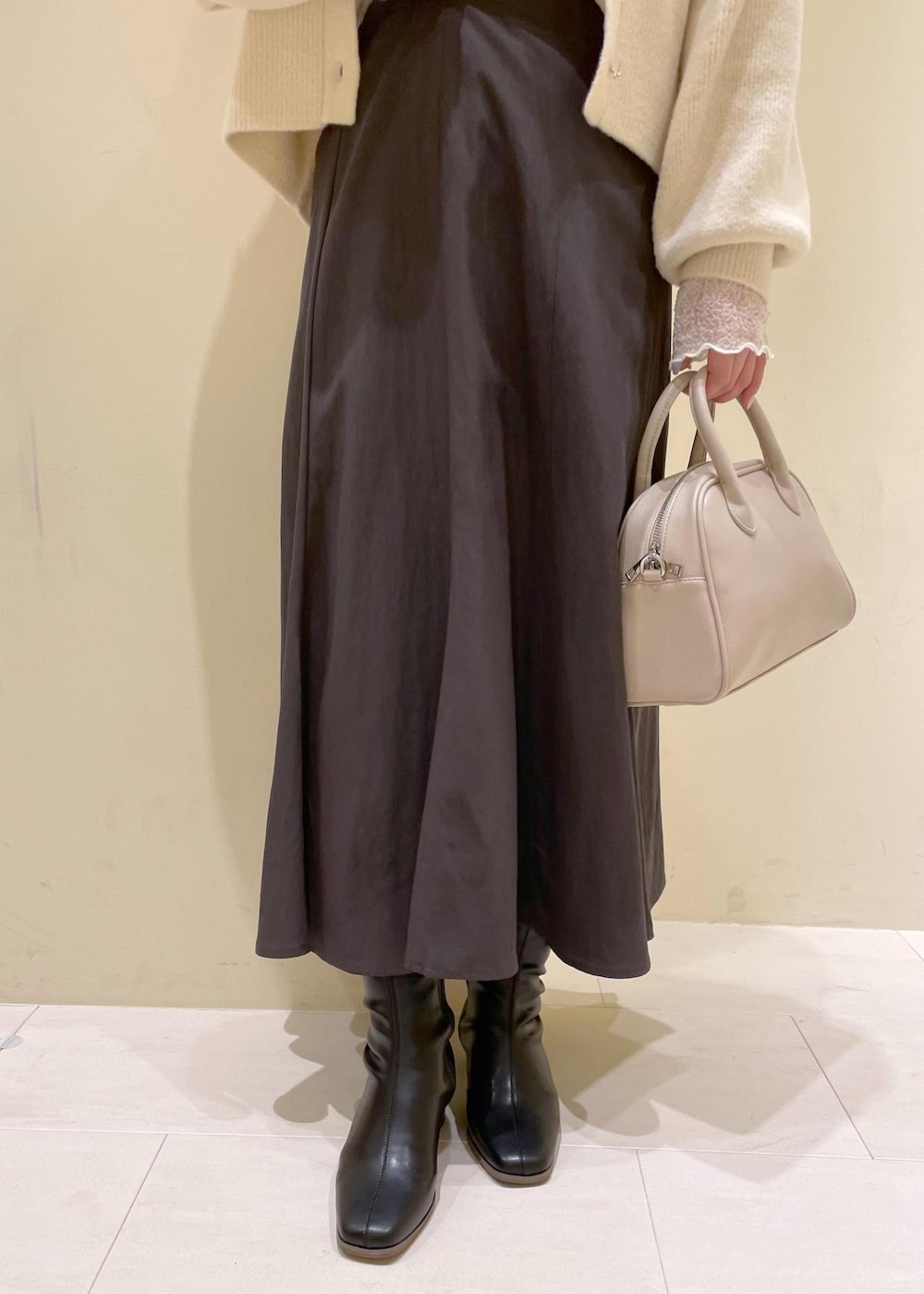 グレー系のスカート、ホワイト系のカーディガン/ボレロ、ホワイト系のTシャツ/カットソーを着用したレディースの秋コーディネートの6枚目の写真