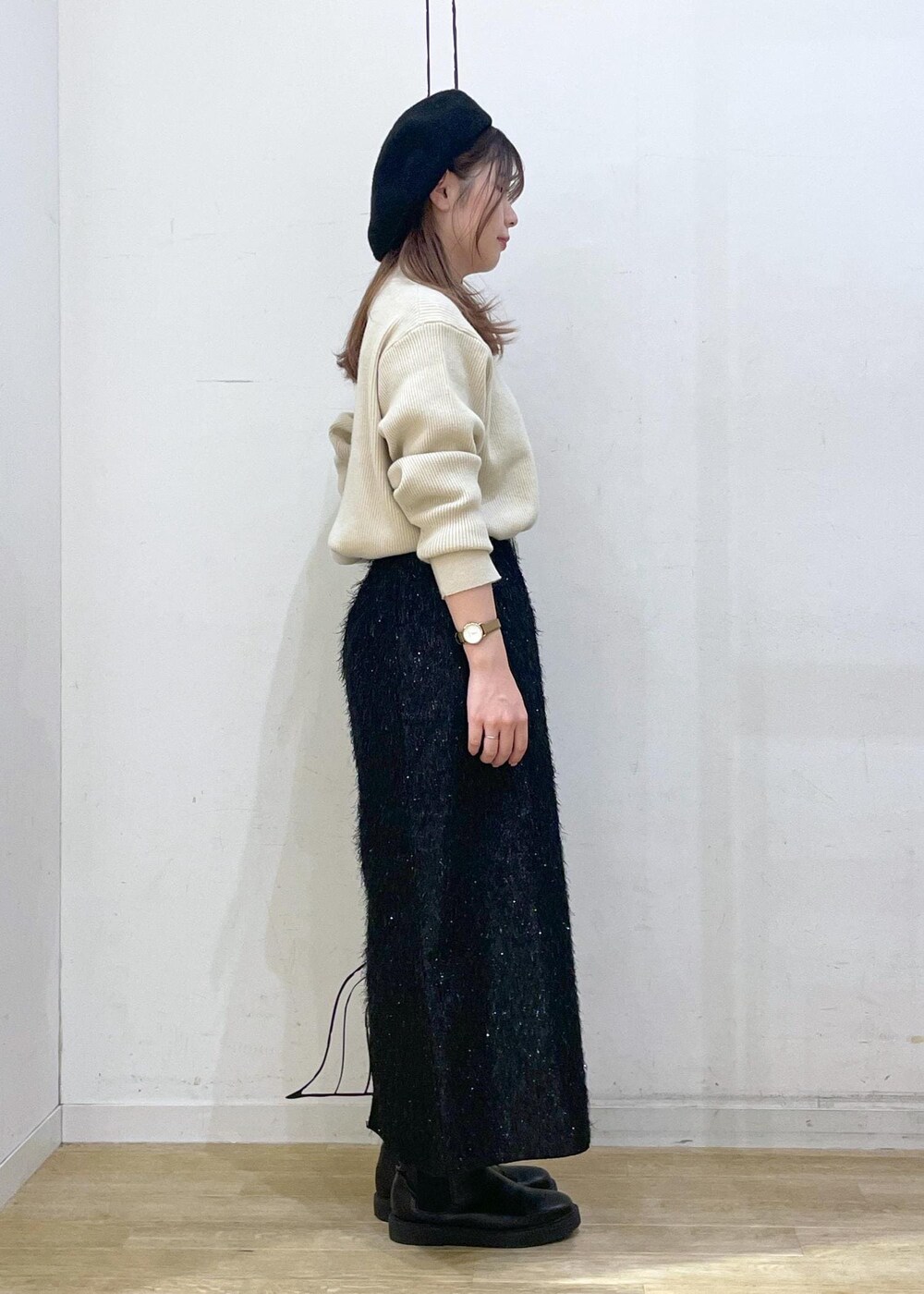 ブラック系のスカート、ベージュ系のニット/セーター、ブラック系のブーツを着用したレディースの冬コーディネートの3枚目の写真