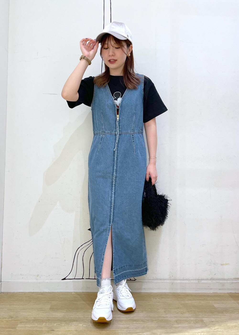 ホワイト系のスニーカー、ブラック系のハンドバッグ、ブルー系のジャンパースカートを着用したレディースの夏コーディネートの2枚目の写真