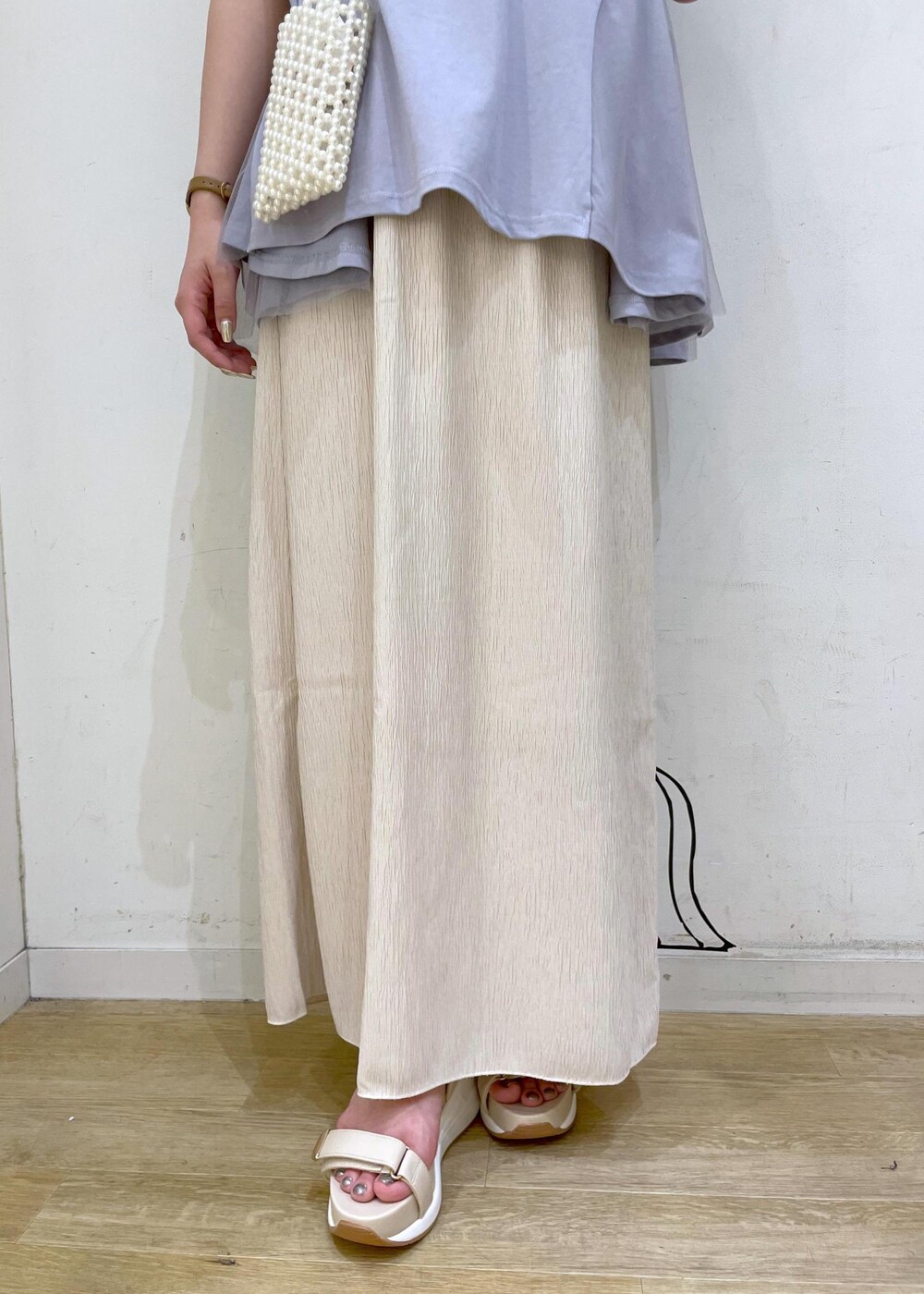 ベージュ系のスカート、ブルー系のTシャツ/カットソー、ホワイト系のサンダルを着用したレディースの夏コーディネートの7枚目の写真