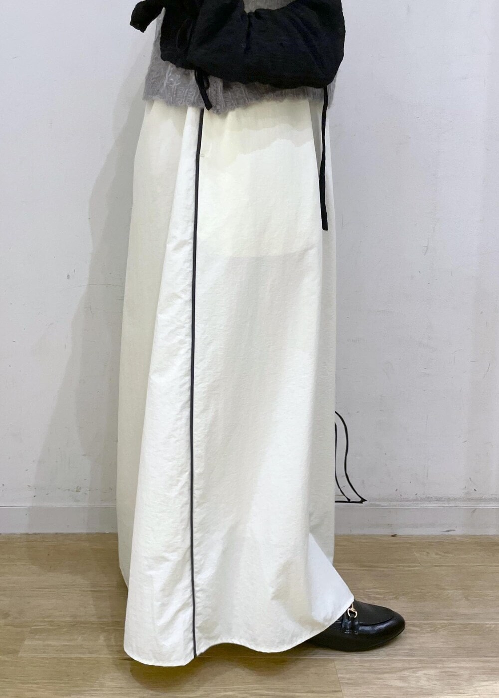 ブラック系のローファー、ホワイト系のスカート、グレー系のニット/セーターを着用したレディースの秋コーディネートの7枚目の写真