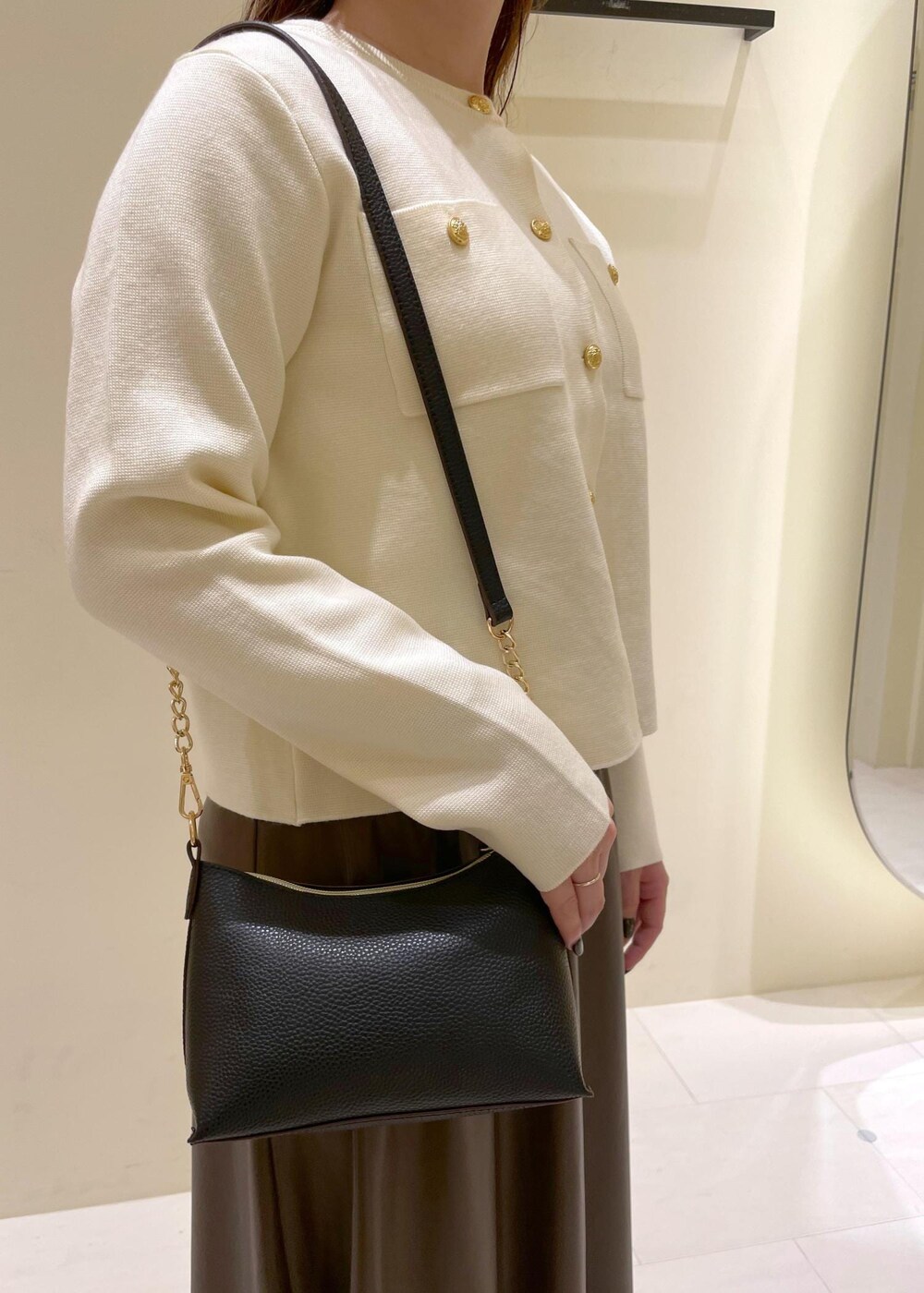 ブラック系のショルダーバッグ、ブラウン系のスカート、ホワイト系のカーディガン/ボレロを着用したレディースの秋コーディネートの6枚目の写真