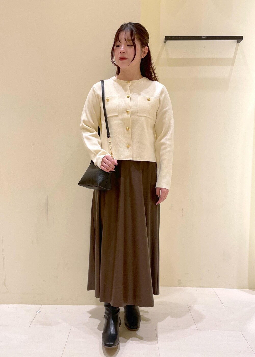ブラック系のショルダーバッグ、ブラウン系のスカート、ホワイト系のカーディガン/ボレロを着用したレディースの秋コーディネートの4枚目の写真