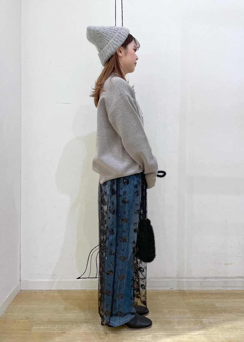 ブラック系のスカート、グレー系のニット/セーター、ブラック系のブーツを着用したレディースの秋コーディネートの3枚目の写真