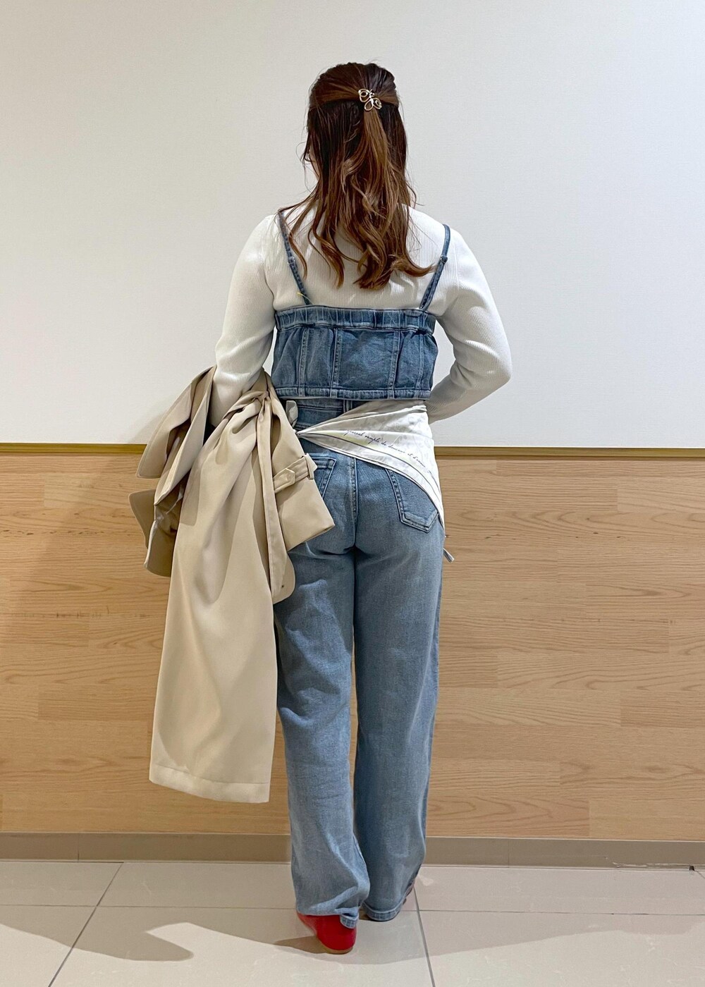 ブルー系のベスト、ホワイト系のニット/セーター、ベージュ系のトレンチコートを着用したレディースの春コーディネートの2枚目の写真