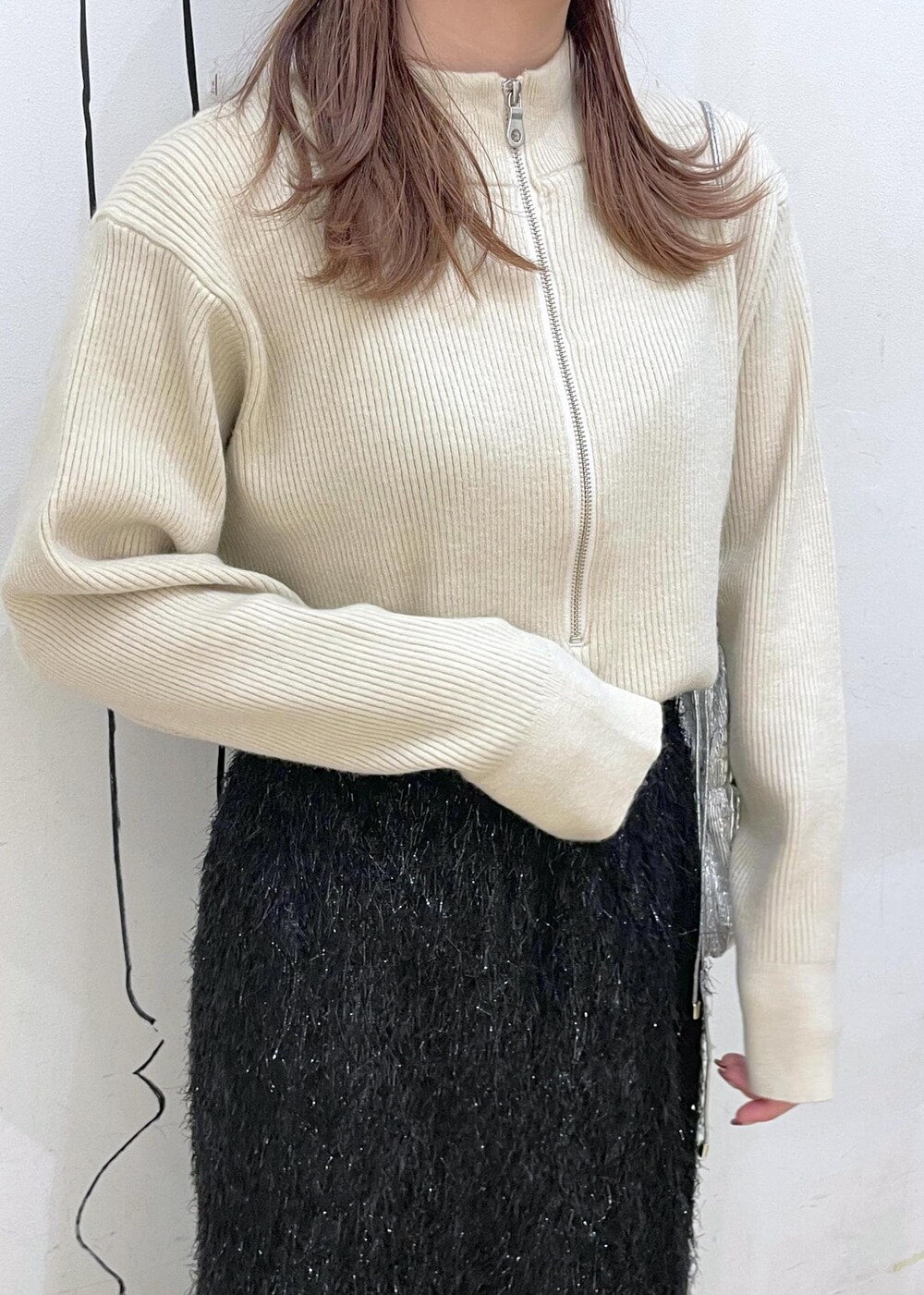 ブラック系のスカート、ベージュ系のニット/セーター、ブラック系のブーツを着用したレディースの冬コーディネートの5枚目の写真