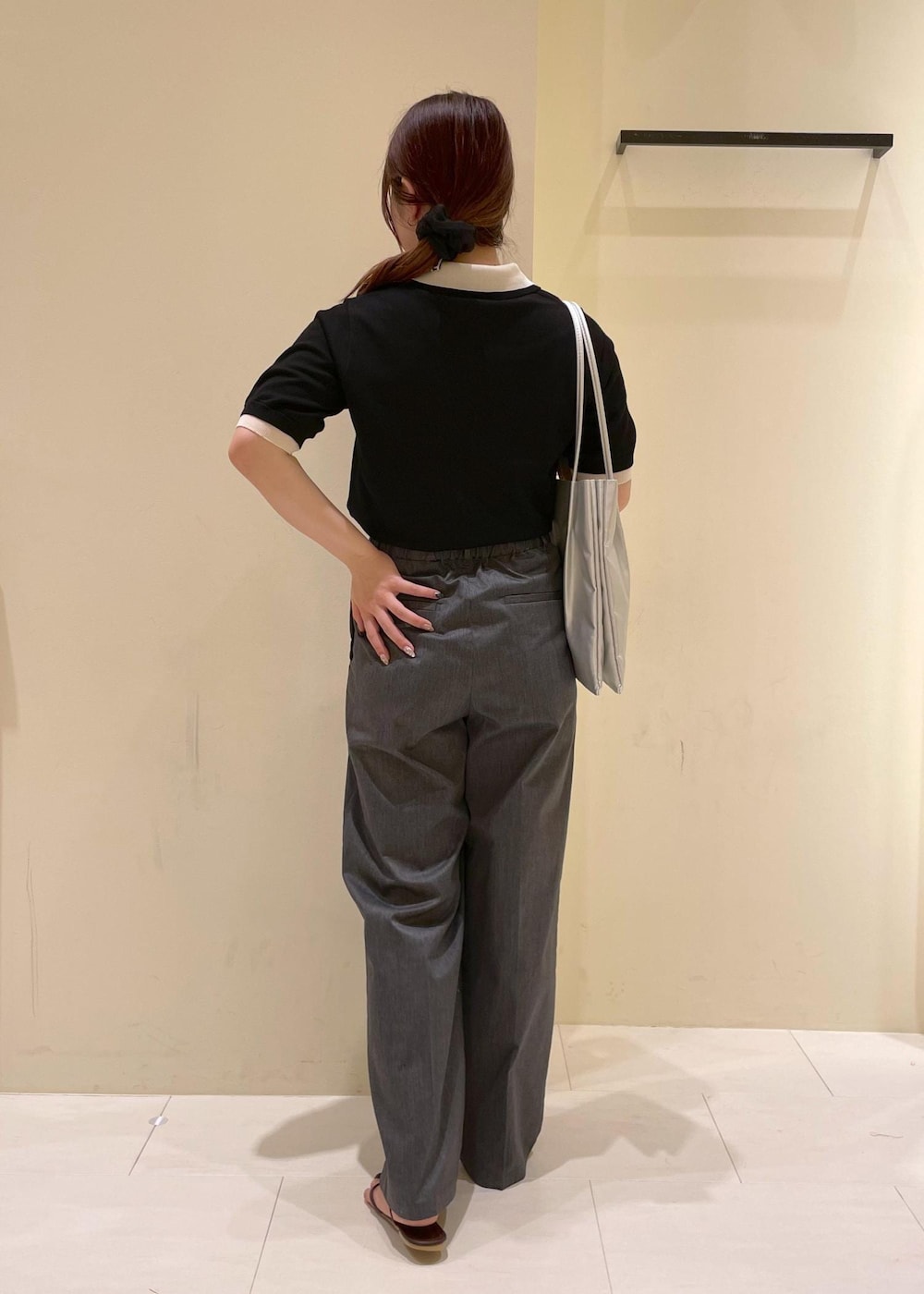 シルバー系のトートバッグ、ブラウン系のサンダル、ブラック系のポロシャツを着用したレディースの夏コーディネートの2枚目の写真