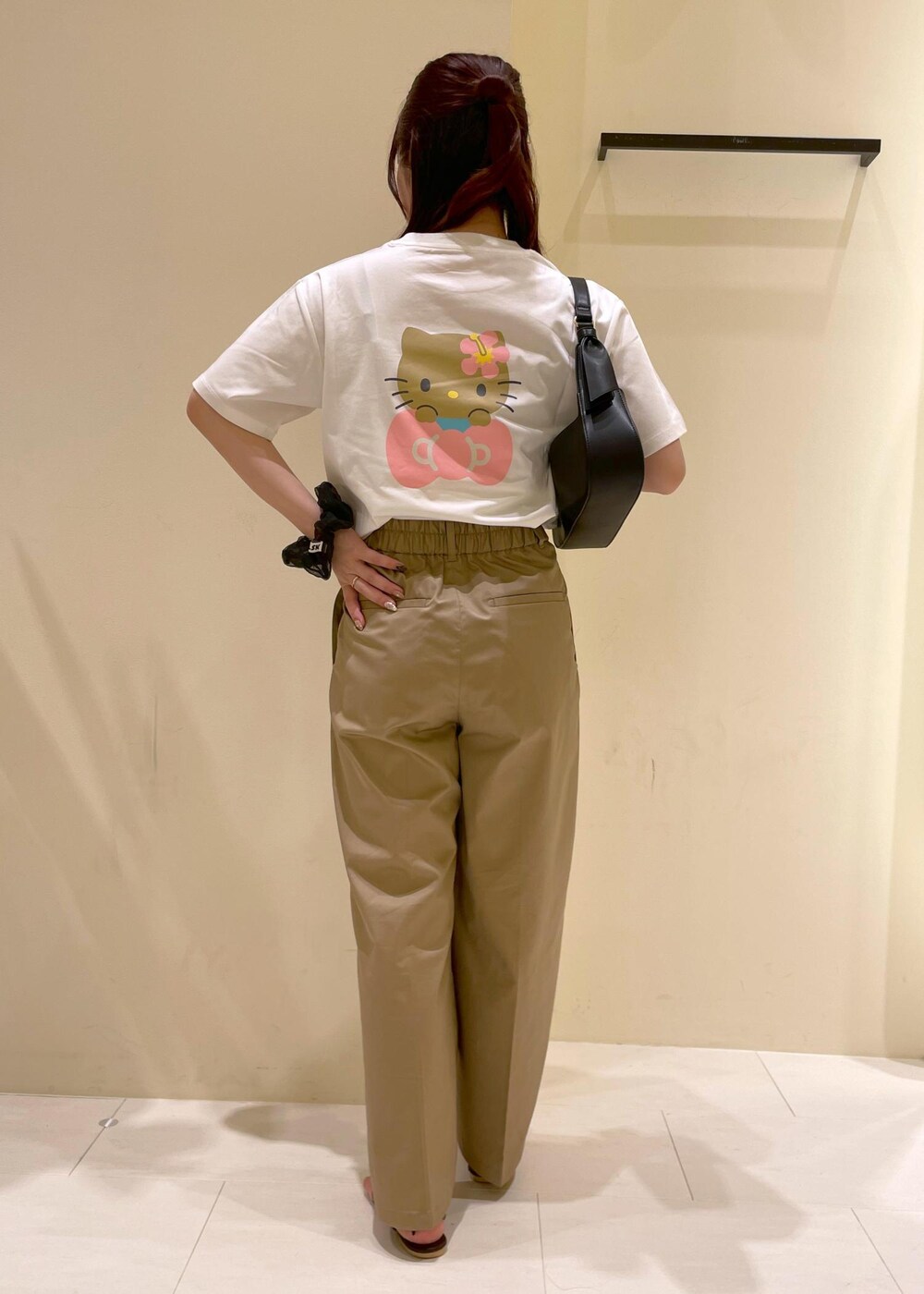 ベージュ系のチノパンツ、ブラウン系のサンダル、ブラック系のハンドバッグを着用したレディースの夏コーディネートの2枚目の写真