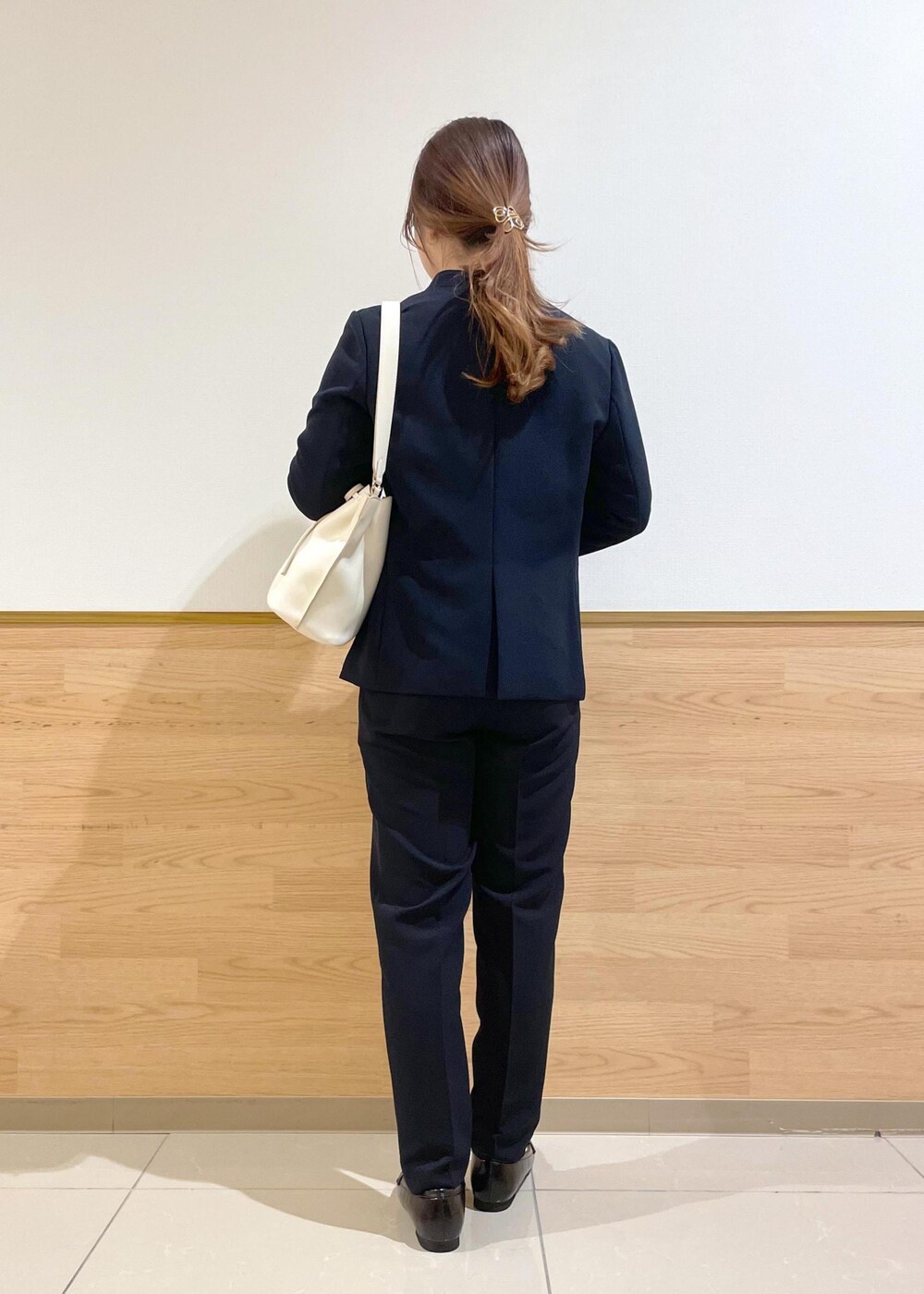 ホワイト系のハンドバッグ、ブラック系のパンプス、ブルー系のノーカラージャケットを着用したレディースの春コーディネートの2枚目の写真