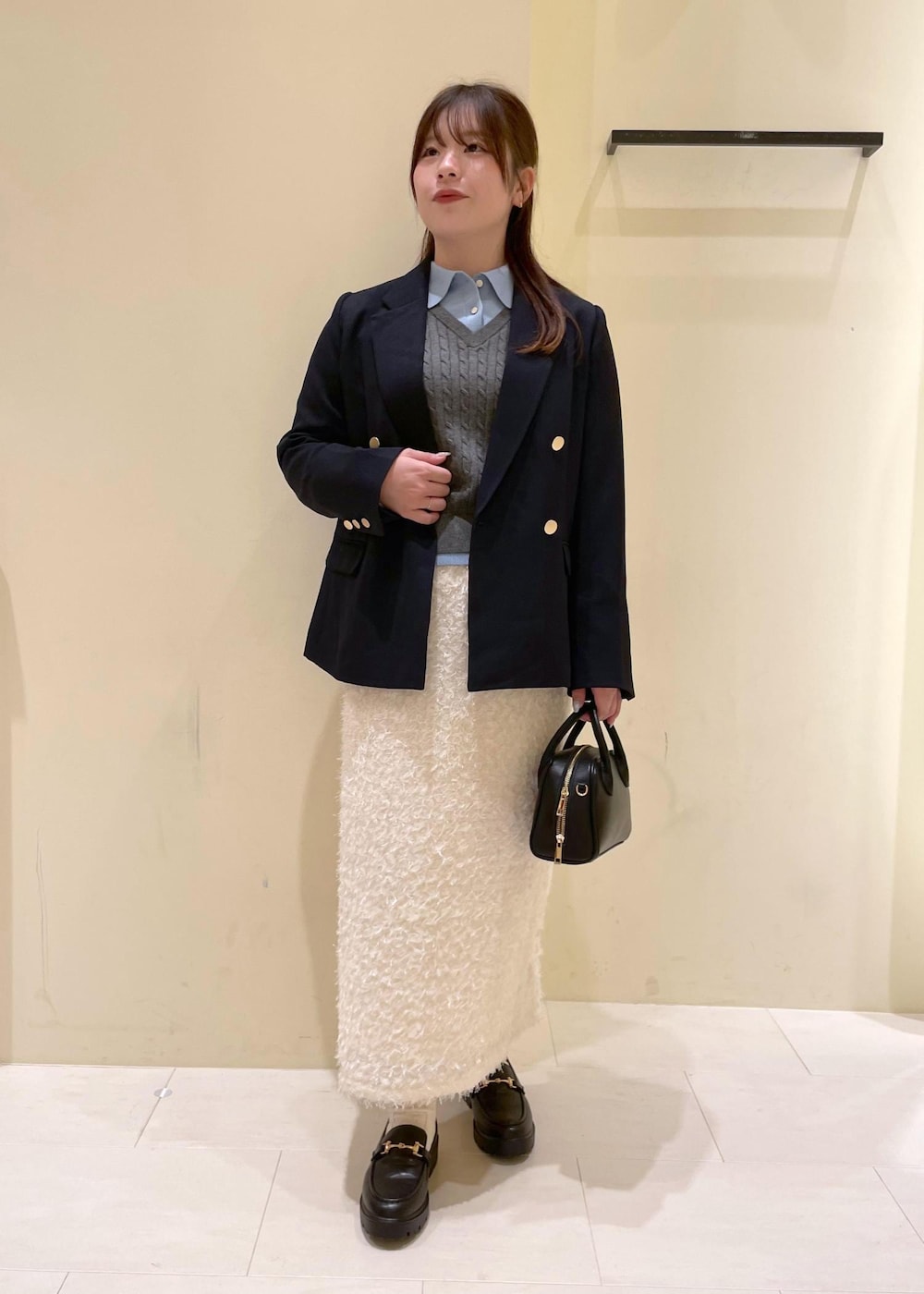 ブラック系のショルダーバッグ、ホワイト系のスカート、ブラック系のローファーを着用したレディースの秋コーディネートの6枚目の写真