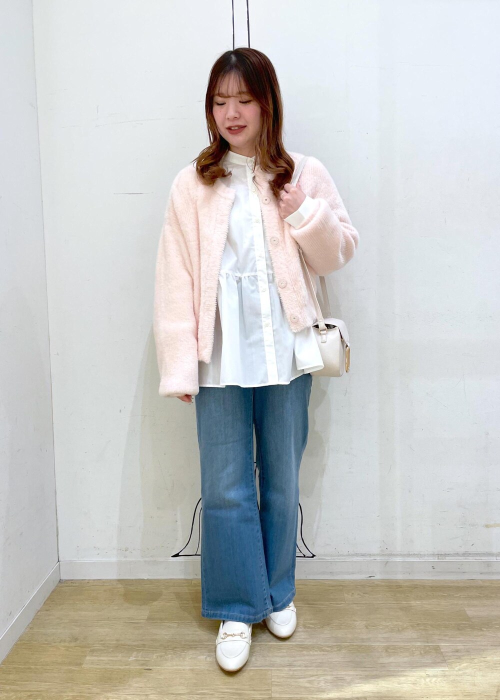 ブルー系のデニムパンツ、ホワイト系のショルダーバッグ、ホワイト系のパンプスを着用したレディースの冬コーディネートの4枚目の写真