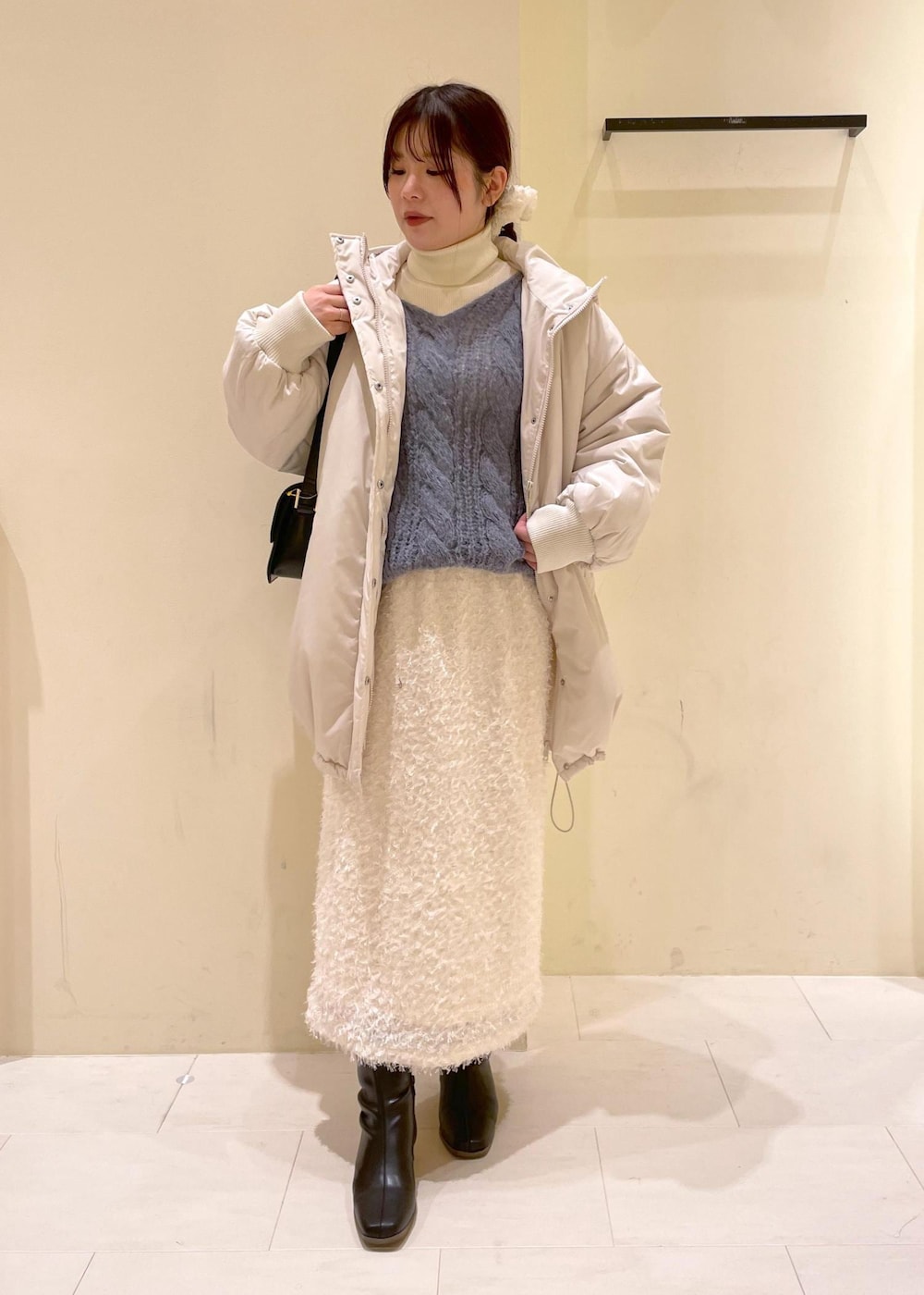 ブラック系のショルダーバッグ、ホワイト系のニット/セーター、ブラック系のブーツを着用したレディースの秋コーディネートの9枚目の写真