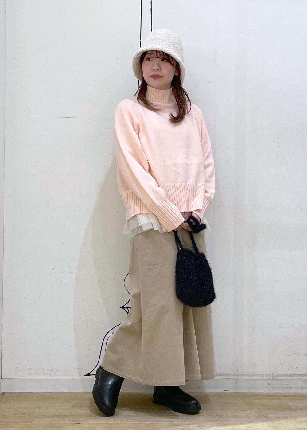 ピンク系のニット/セーター、ブラック系のブーツ、ブラック系のショルダーバッグを着用したレディースの冬コーディネートの4枚目の写真