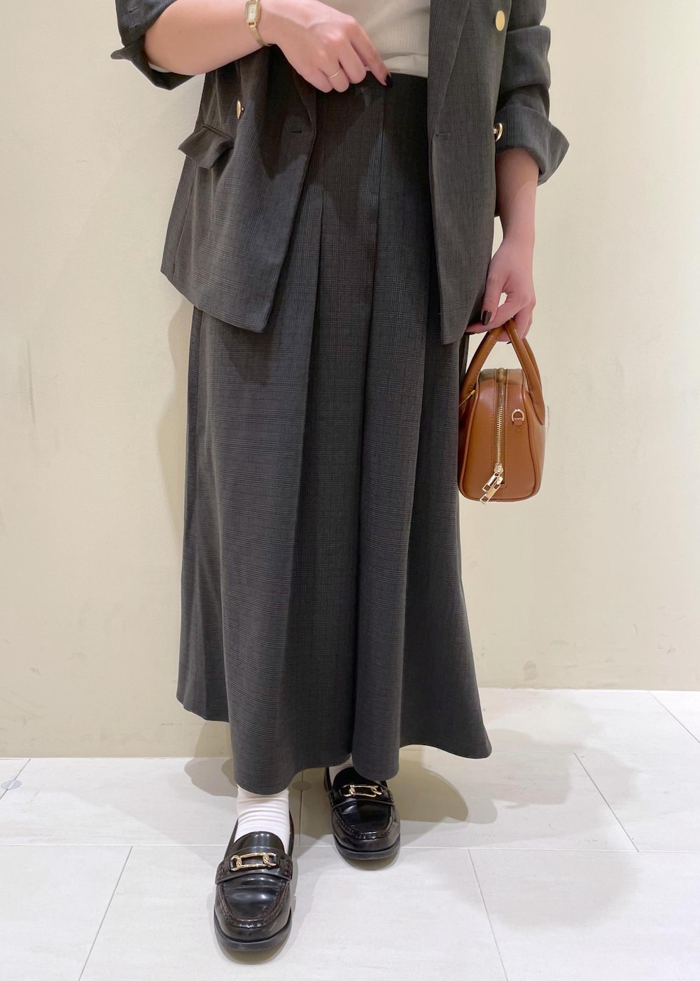 ブラック系のスカート、ブラック系のテーラードジャケット、ベージュ系のTシャツ/カットソーを着用したレディースの秋コーディネートの7枚目の写真