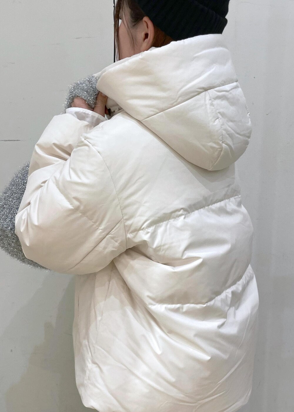 ベージュ系のダウンジャケット/コート、シルバー系のショルダーバッグ、ブルー系のニット/セーターを着用したレディースの冬コーディネートの6枚目の写真