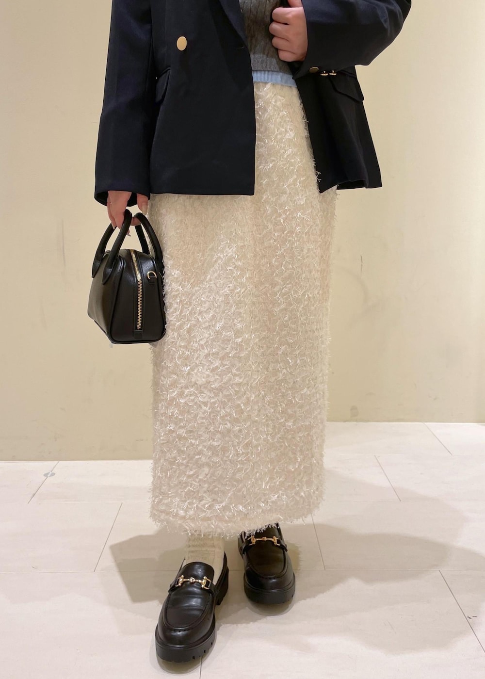 ブラック系のショルダーバッグ、ホワイト系のスカート、ブラック系のローファーを着用したレディースの秋コーディネートの8枚目の写真