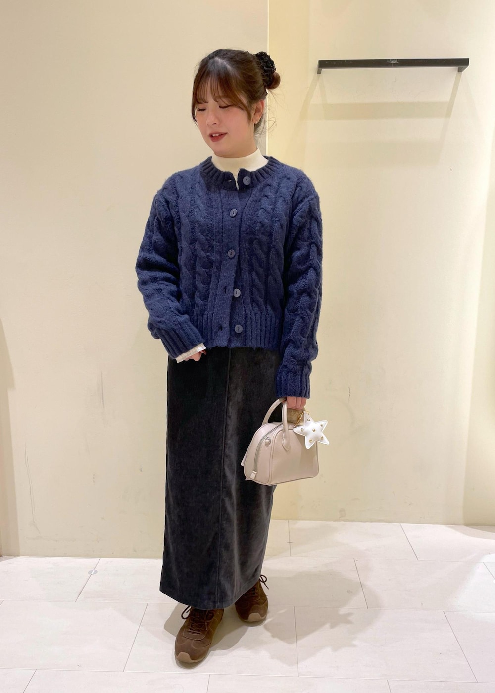 グレー系のスカート、ブルー系のカーディガン/ボレロ、ホワイト系のニット/セーターを着用したレディースの冬コーディネートの4枚目の写真