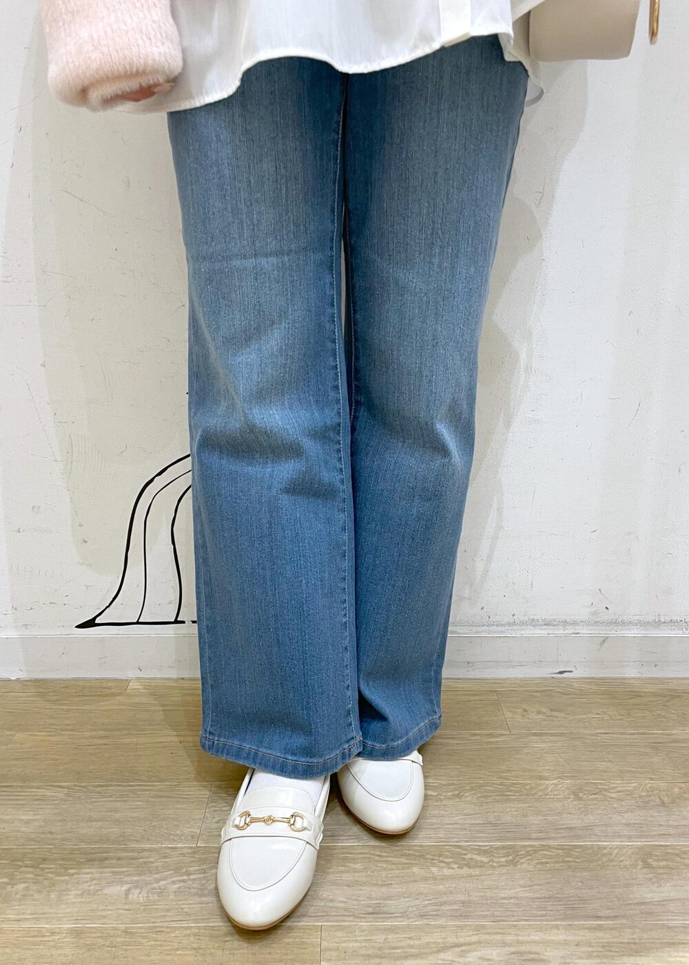 ブルー系のデニムパンツ、ホワイト系のショルダーバッグ、ホワイト系のパンプスを着用したレディースの冬コーディネートの7枚目の写真